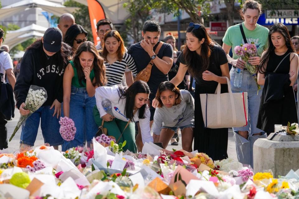 People place flowers at the scene on Monday (AP)