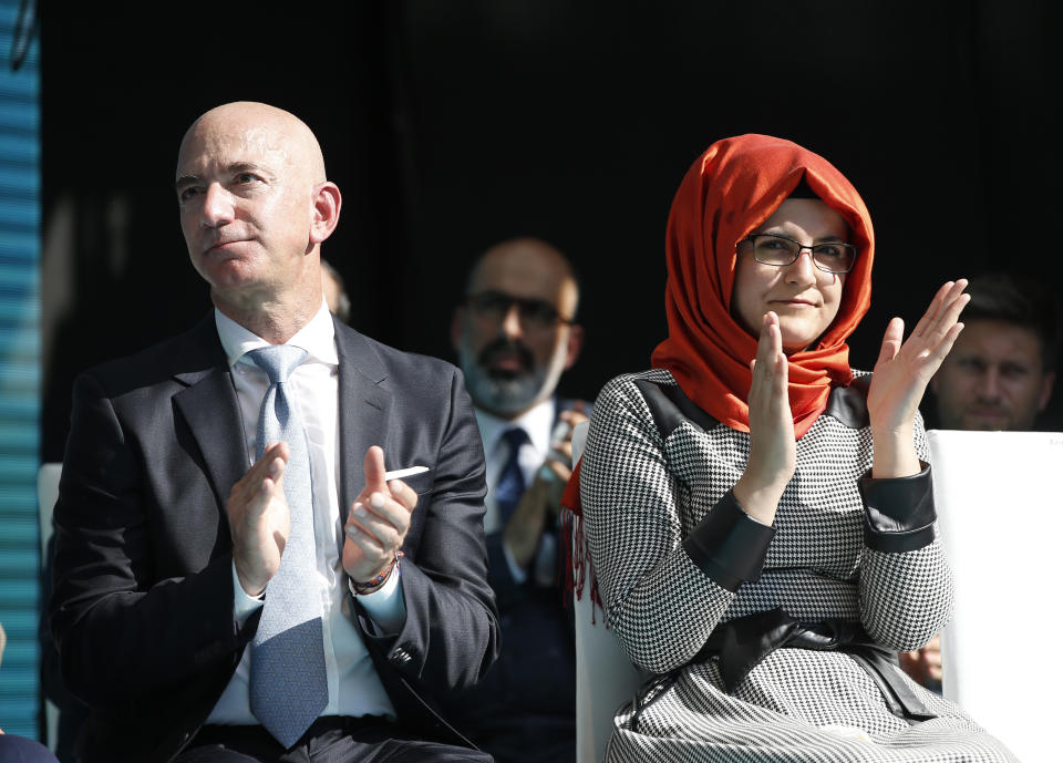 Washington Post owner Jeff Bezos, left, and Hatice Cengiz, right, the fiancee of slain Saudi journalist Jamal Kashoggi, applaud a speaker during a ceremony near the Saudi Arabia consulate in Istanbul, marking the one-year anniversary of his death, Wednesday, Oct. 2, 2019. A vigil was held outside the consulate building Wednesday, starting at 1:14 p.m. (1014 GMT) marking the time Khashoggi walked into the building where he found tragic death. (AP Photo/Lefteris Pitarakis)