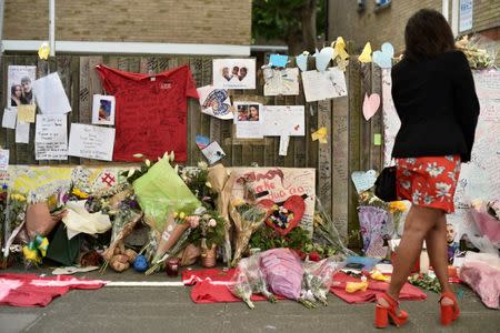 A woman looks at flowers, tributes and messages left for the victims of the fire at the Grenfell apartment tower in North Kensington, London, Britain, June 23, 2017. REUTERS/Hannah McKay