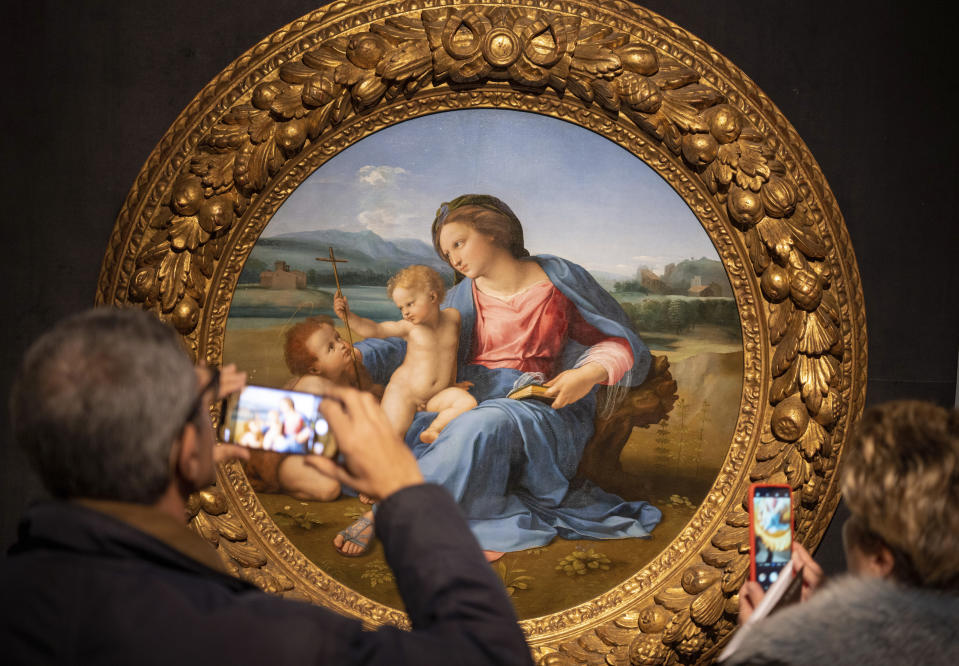 Visitors take photos of Raphael's painting Virgin with Child and Infant St. John the Baptist, at a press preview of Raphael's exhibition in Rome, Wednesday, March 4, 2020. The paintings, drawings and sketches in the most ambitious assemblage ever of Raphael works in an exhibition, more than even the Renaissance superstar had in his workshop at one time, are collectively insured for 4 billion euros, against the likes of theft or vandalism. But no money can guarantee that Italy’s outbreak of coronavirus, the largest in Europe, won’t play havoc with the three-month run in Rome of the art world’s eagerly-awaited blockbuster. (AP Photo/Domenico Stinellis)