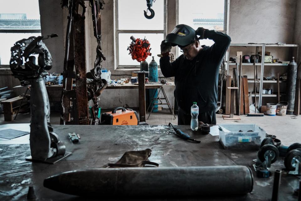 A man puts on a welding mask in a studio