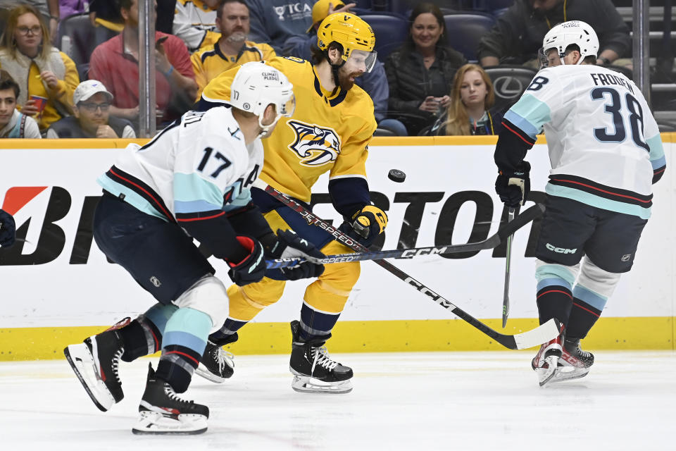 Nashville Predators' Tommy Novak, center, tries to get control of the puck as Seattle Kraken center Jaden Schwartz (17) and right wing Jesper Froden (38) defend during the first period of an NHL hockey game Thursday, March 23, 2023, in Nashville, Tenn. (AP Photo/Mark Zaleski)