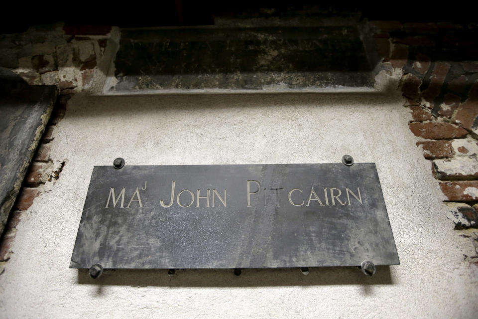 In this Wednesday, Nov. 7, 2018 photo, a plaque marks the tomb of Revolutionary War British Marine Major John Pitcairn in the basement of Old North Church, in Boston. Pitcairn was buried at the church after he was mortally wounded during the 1775 Battle of Bunker Hill. A bronze wreath and plaque that forms part of a memorial, which includes thousands of dog tags honoring soldiers killed in Iraq and Afghanistan, has been installed on the grounds of the church. The new plaque and wreath help explain the meaning of the dog tags and acknowledge Britain's contribution and sacrifice. (AP Photo/Steven Senne)