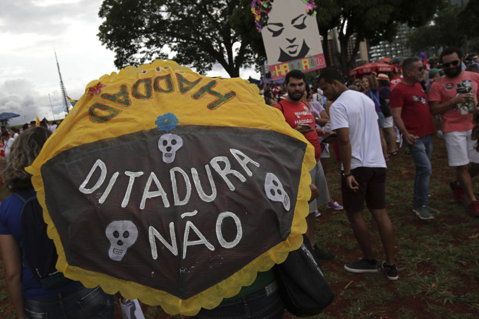 A demonstrator walks with an umbrella that has text written in Portuguese that reads "Dictatorship No, Haddad Yes", during a protest called "Women against Bolsonaro," in Brasilia, Brazil, on Saturday, Oct. 20, 2018. Women and left-wing militants held protests across the country against the right-wing presidential candidate Jair Bolsonaro. (AP Photo/Eraldo Peres)