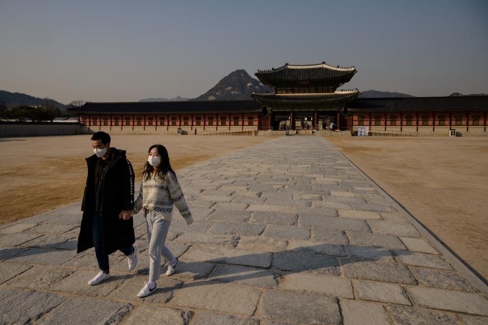 Visitors wearing face masks, amid concerns about the spread of the COVID-19 novel coronavirus, walk through a courtyard of Gyeongbokgung palace in central Seoul on March 6, 2020. Seoul threatened to retaliate on March 6 over what it called Tokyo's "irrational" plan to quarantine arrivals from South Korea over the coronavirus outbreak, turning the scientific issue into a diplomatic row. (Photo by ED JONES/AFP via Getty Images)