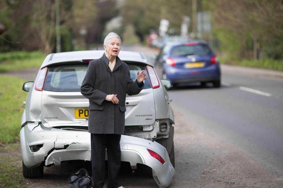 A woman waiting beside a damaged car (PA Archive)