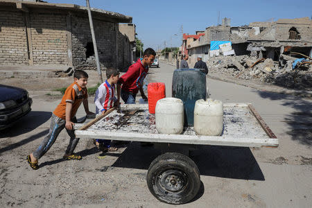 Children push water containers on a street in eastern Mosul, Iraq, April 19, 2017. REUTERS/Marko Djurica