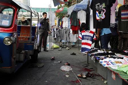 A policeman talks on his phone at the crime scene following an a bomb blast in Bangkok February 23, 2014. REUTERS/Paul Barker