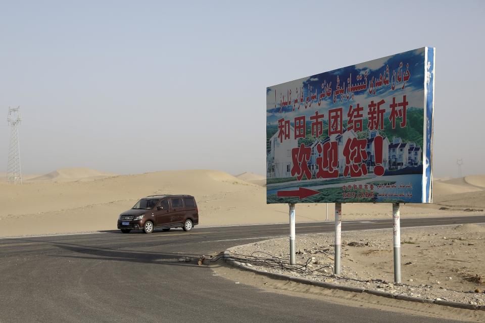 FILE - A car drives through a desert where a signboard which reads "Welcome to the Hotan Unity New Village" is seen on display in Hotan, in western China's Xinjiang region on Sept. 21, 2018. Authorities in China's western Xinjiang region have been systematically replacing the names of villages inhabited by Uyghurs and other ethnic minorities to reflect the ruling Communist Party's ideology, as part of an attack on their cultural identity, according to a report released Wednesday, June 19, 2024 by Human Rights Watch. (AP Photo/Andy Wong, File)