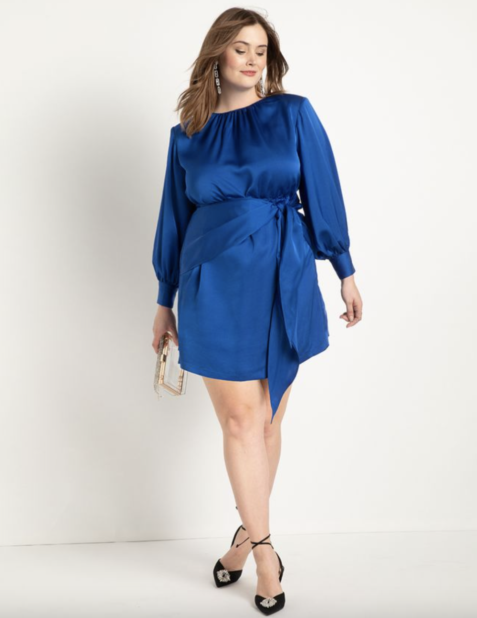 brunette plus size model in cobalt blue Eloquii Satin Strong Shoulder Dress (Photo via Eloquii)