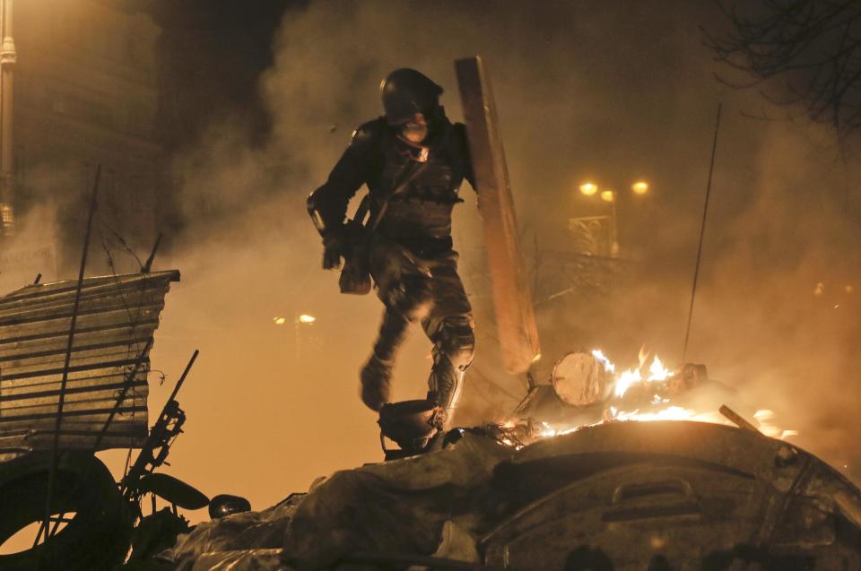 An anti-government protester runs during clashes with riot police in Kiev's Independence Square, the epicenter of the country's current unrest, Kiev, Ukraine, Tuesday, Feb. 18, 2014. Thousands of police armed with stun grenades and water cannons attacked a large opposition camp in Ukraine's capital on Tuesday that has been the center of nearly three months of anti-government protests after at least nine people were killed in street clashes. (AP Photo/Efrem Lukatsky)