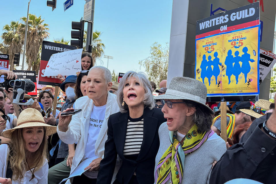 Actress and activist Jane Fonda, center in dark jacket, and her "9 to 5" co-star Lily Tomlin, right, joined by the 1980 film's screenwriter Patricia Resnick, left in white jacket, cheer during a "Striking 9 to 5" picket line in front of Netflix headquarters, in Hollywood, CA, Thursday, June 29, 2023.