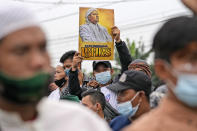 A supporter holds up a poster bearing a portrait of firebrand cleric Rizieq Shihab during a rally near the district court where his sentencing hearing is held in Jakarta, Indonesia, Thursday, June 24, 2021. The influential cleric was sentenced to another four years in prison on Thursday for concealing information about his coronavirus test result. Writings on the poster read "We are with Grand Imam Rizieq Shihab."(AP Photo/Dita Alangkara)