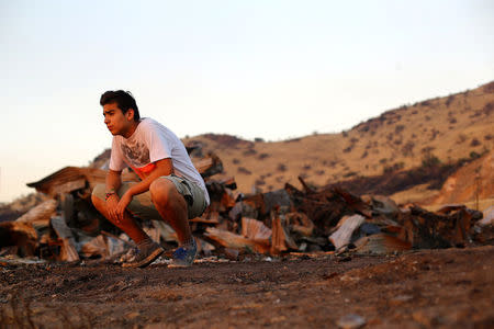 Peruvian immigrant, Anthony Altamirano, takes a break next to debris of his home at a shack camp after an accidental fire in Santiago, Chile, December 14, 2016. Picture taken December 14, 2016. REUTERS/Ivan Alvarado