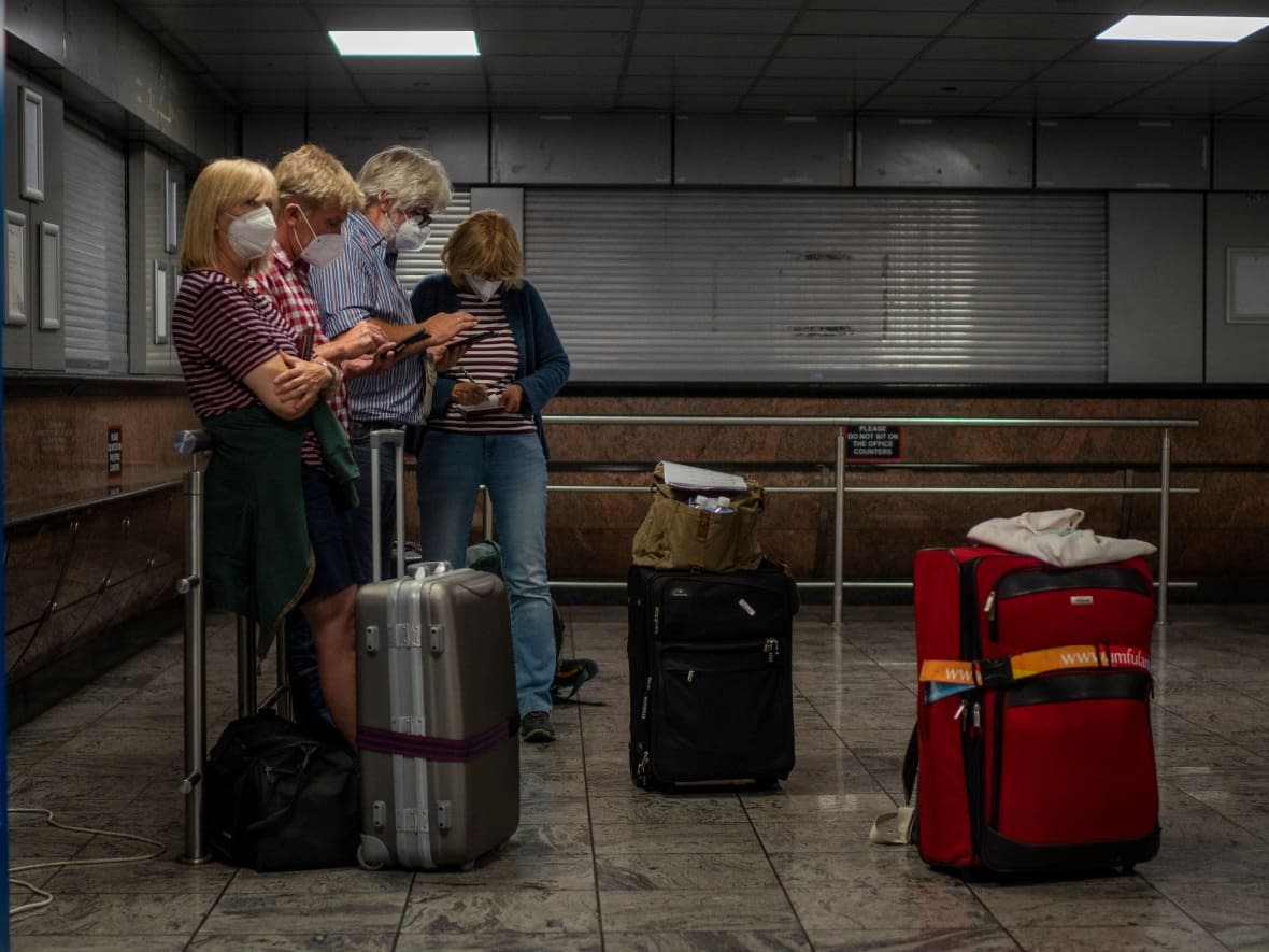 Passenger check their phones at Johannesburg's OR Tambo's airport, Monday Nov. 29, 2021, days after Canada announced travel restrictions on several countries after the discovery of the omicron variant in South Africa. (Jerome Delay/AP - image credit)