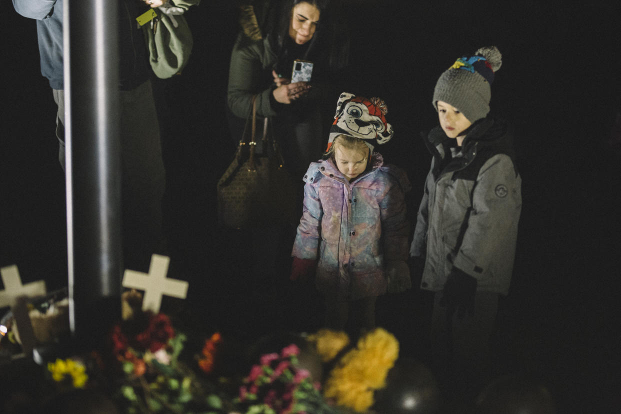 Two children leave items at a makeshift memorial for victims of the deadly holiday parade incident in Waukesha, Wisconsin.