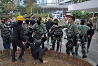 Riot police chase and corner a masked man who fell as another man tries to assist him ahead of a rally demanding electoral democracy and call for boycott of the Chinese Communist Party and all businesses seen to support it in Hong Kong, Sunday, Jan. 19, 2020. Hong Kong has been wracked by often violent anti-government protests since June, although they have diminished considerably in scale following a landslide win by opposition candidates in races for district councilors late last year. (AP Photo/Ng Han Guan)