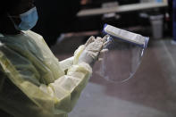 FILE - In this May 21, 2020, file photo, a registered nurse cleans personal protective equipment before the opening of a temporary coronavirus testing facility for casino employees at the Las Vegas Convention Center in Las Vegas. States are spending billions of dollars stocking up on medical supplies like masks and breathing machines during the coronavirus pandemic. An Associated Press survey of all 50 states found a hodgepodge of public information about the purchase of masks, gloves, gowns and other hard-to-get equipment for medical and emergency workers. (AP Photo/John Locher, File)