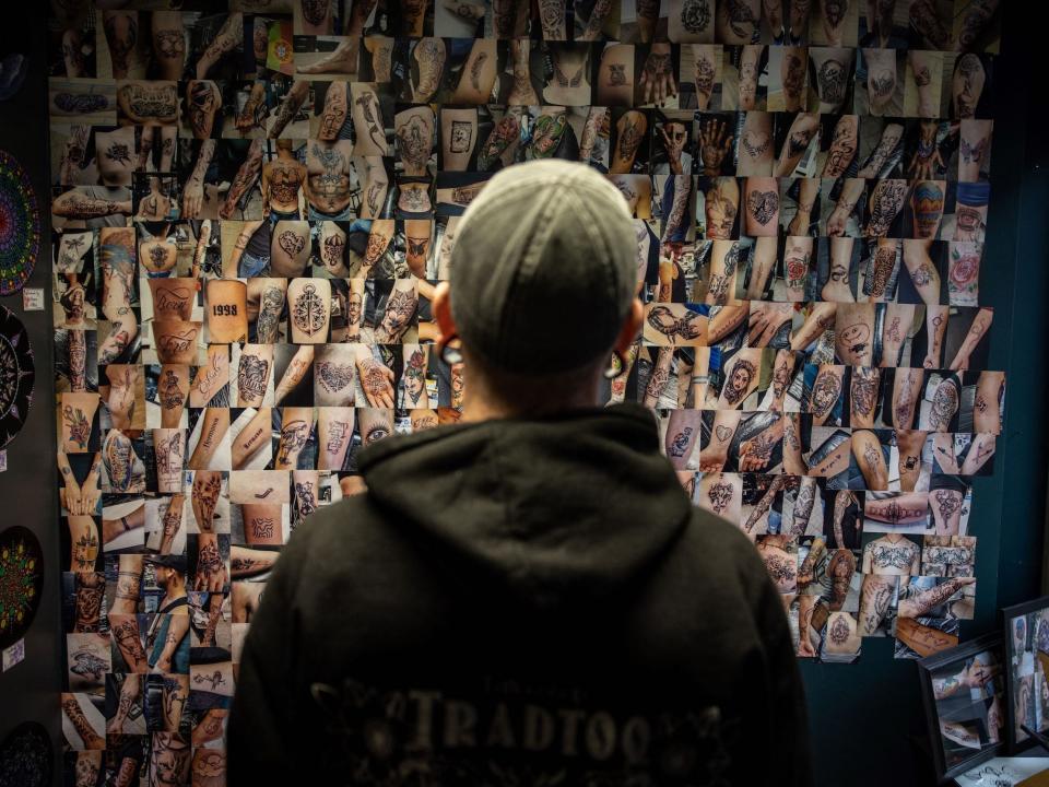 Darryl Veer, owner of tattoo shop "Tradtoo," looks at pictures of previous tattoos