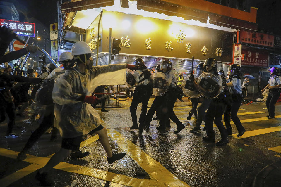 Policemen are confronted by demonstrators on a street during a protest in Hong Kong, Sunday, Aug. 25, 2019. Hong Kong police have rolled out water cannon trucks for the first time in this summer's pro-democracy protests. The two trucks moved forward with riot officers Sunday evening as they pushed protesters back along a street in the outlying Tsuen Wan district. (AP Photo/Kin Cheung)