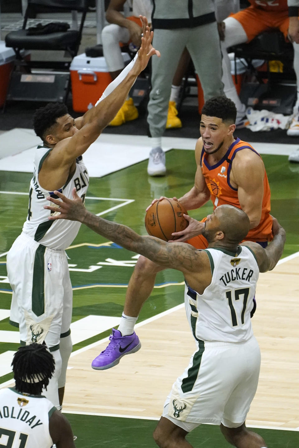 Phoenix Suns guard Devin Booker, center, drives between Milwaukee Bucks forward Giannis Antetokounmpo, left, and forward P.J. Tucker (17) during the second half of Game 4 of basketball's NBA Finals in Milwaukee, Wednesday, July 14, 2021. (AP Photo/Paul Sancya)