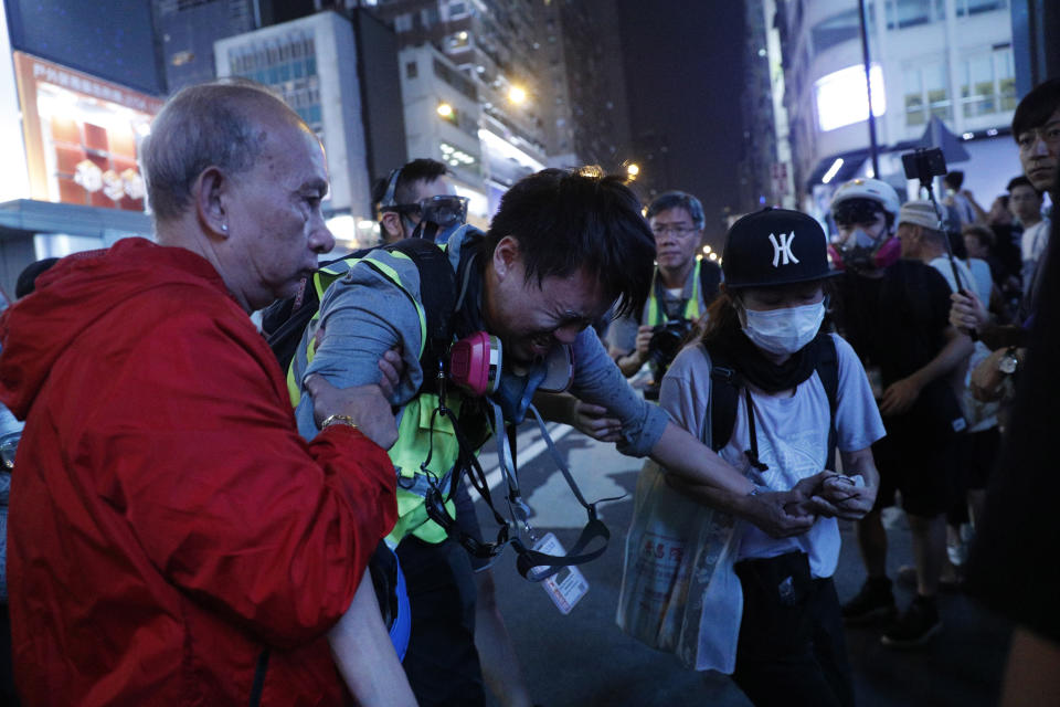 A journalist is assisted after getting hit by pepper spray during a rally in Hong Kong on Sunday, Oct. 27, 2019. Hong Kong police fired tear gas Sunday to disperse a rally called over concerns about police conduct in monthslong pro-democracy demonstrations, with protesters cursing the officers and calling them "gangster cops." (AP Photo/Kin Cheung)