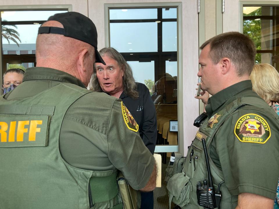 Christian Gardinier, who was told to leave the Tuesday, Aug. 29, 2023, Shasta County Board of Supervisors meeting, talks to sheriff's deputies outside the meeting chamber.
