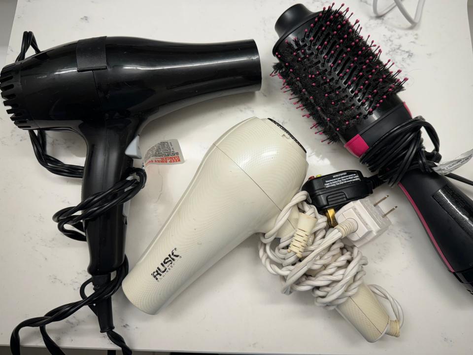 blow dryers and styling brushes on a bathroom counter