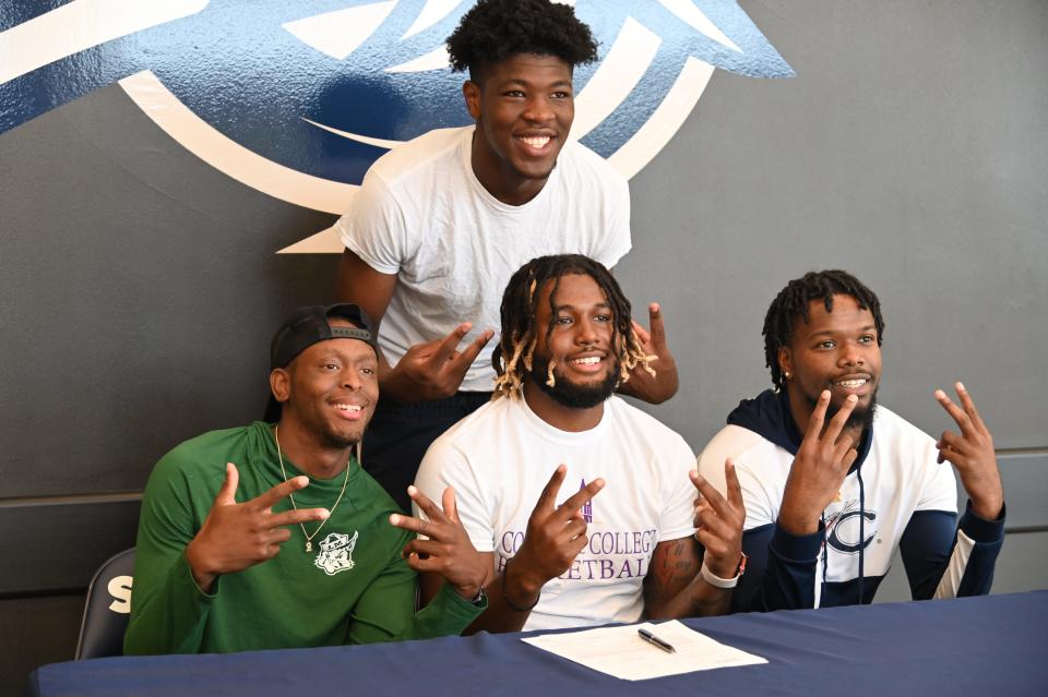 Davidson-Davie Community College Storm teammates join Uzziah Dawkins, center, after Dawkins signed his letter of intent to play basketball at Converse.