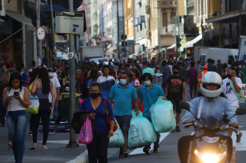 Personas caminan con bolsas en una popular calle comercial en medio del brote de COVID-19 en Sao Paulo, Brasil. 19 de junio de 2020.