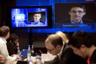 Edward Snowden, displayed on television screens, asks a question to Russian President Vladimir Putin during a nationally televised question-and-answer session, in Moscow, Thursday, April 17, 2014. Speaking in a televised call-in show with the nation, Putin harshly criticized the West for trying to pull Ukraine into its orbit and said that people in eastern Ukraine have risen against the authorities in Kiev, who ignored their rights and legitimate demands. Putin also took a video question from National Security Agency leaker Edward Snowden, whom Russia granted asylum last year. Asked by Snowden about Russia's surveillance programs, Putin said that Russian special services also tap on communications in their fight against terrorism, but don't do it on such a massive scale as the U.S. (AP Photo/Pavel Golovkin)