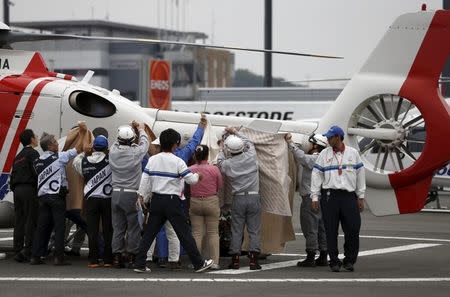 ART E-Motion Iodaracing Team MotoGP rider Alex De Angelis of San Marino is carried into a medical helicopter, after crashing during fourth free practice session for Sunday's Japanese Grand Prix as officials try to cover him using blankets at the Twin Ring Motegi circuit in Motegi, north of Tokyo, Japan, October 10, 2015. REUTERS/Issei Kato