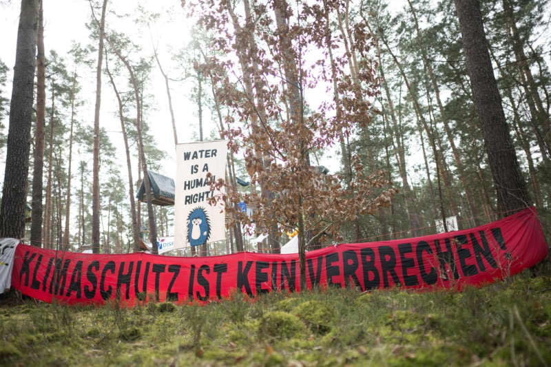 A banner reading "Climate protection is not a crime!" hang on at a camp organized by the "Stop Tesla" initiative in a pine forest near the Tesla Gigafactory Berlin-Brandenburg. The permit for the camp expires this Friday at midnight and is expected to be evacuated next weekend. Sebastian Gollnow/dpa