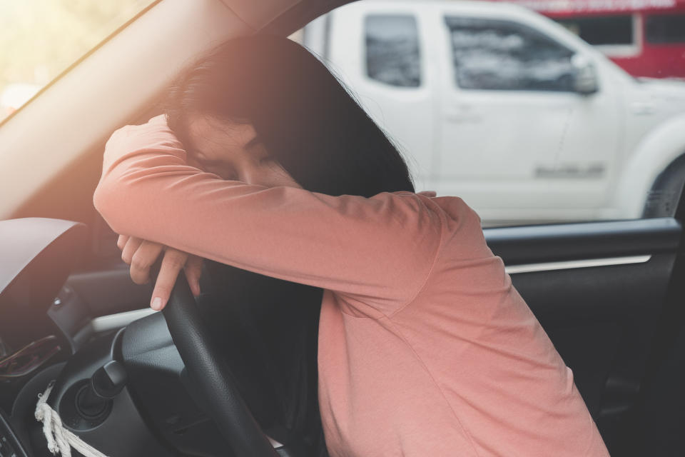 A woman sleeping on a steering wheel