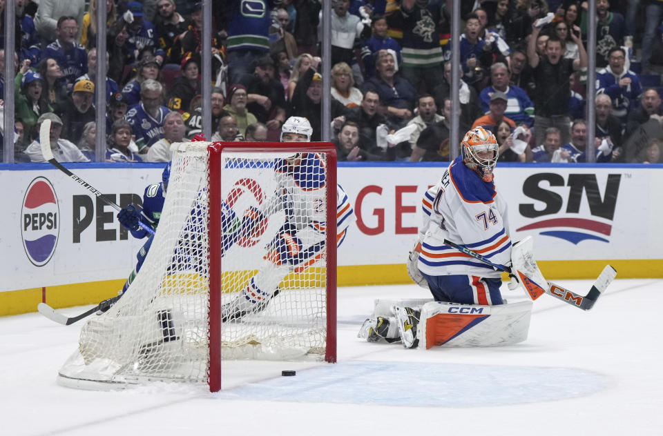 Edmonton Oilers goalie Stuart Skinner (74) looks back at the puck as it bounces out of the net after Vancouver Canucks' Conor Garland, hidden back left, scored during the third period of Game 1 of a second-round NHL hockey Stanley Cup playoffs series, Wednesday, May 8, 2024, in Vancouver, British Columbia. (Darryl Dyck/The Canadian Press via AP)