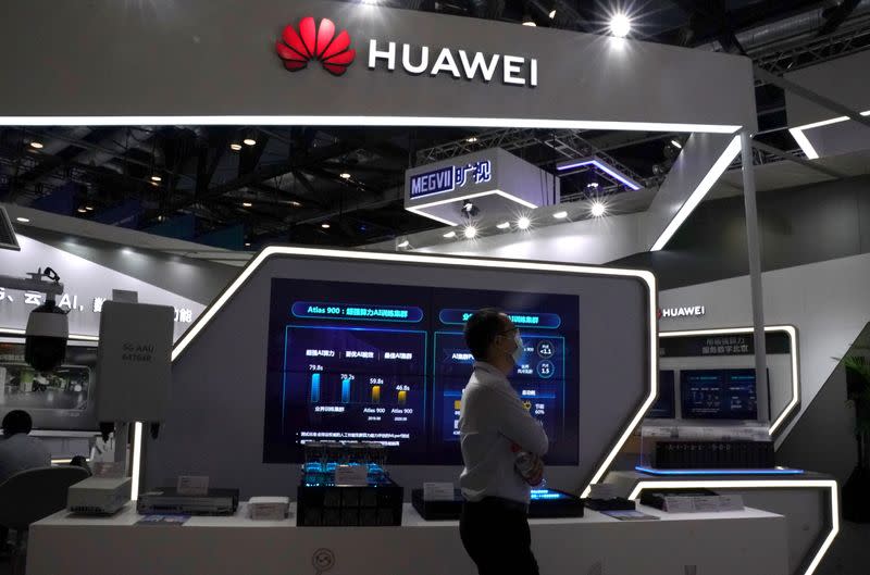FILE PHOTO: Man wearing a face mask following the coronavirus disease (COVID-19) outbreak walks past a booth of Huawei at the 2020 China International Fair for Trade in Services (CIFTIS) in Beijing