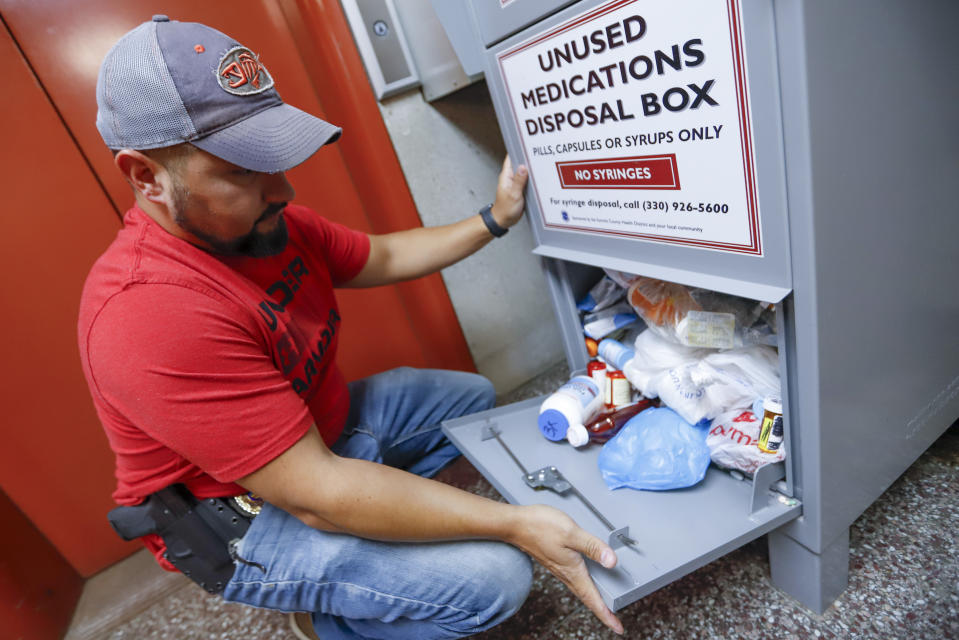 FILE - In this Sept. 11, 2019, photo, narcotics detective Paul Laurella retrieves unused medications from the police department's disposal box in Barberton, Ohio. Jury selection is set to begin Wednesday, Oct. 16, 2019, in the first federal trial over the nation's opioid epidemic. (AP Photo/Keith Srakocic, File)