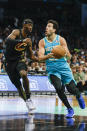 Charlotte Hornets guard Vasilije Micic, right, drives to the basket against Cleveland Cavaliers guard Caris LeVert during the first half of an NBA basketball game in Charlotte, N.C., Wednesday, March 27, 2024. (AP Photo/Nell Redmond)