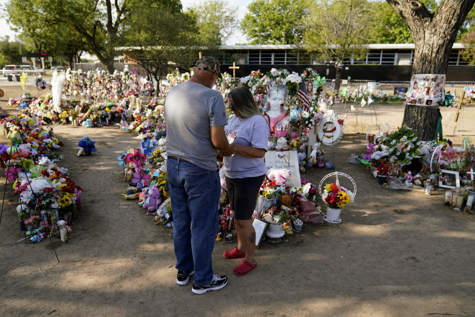 Pastor Wayne Traverse, from Port St.Lucie, Fla., left, prays with a woman at a make-shift memorial honoring the school shooting victims at Robb Elementary, Tuesday, July 12, 2022, in Uvalde, Texas. Students who survived the May 24 shooting at an elementary school in Uvalde, Texas are spending the summer grappling with post-traumatic stress disorder. Meanwhile, parents find themselves unable to help them, worried the tragedy at Robb Elementary struck a largely Hispanic town as Latinos continue to face disparities to access mental health care. (AP Photo/Eric Gay)