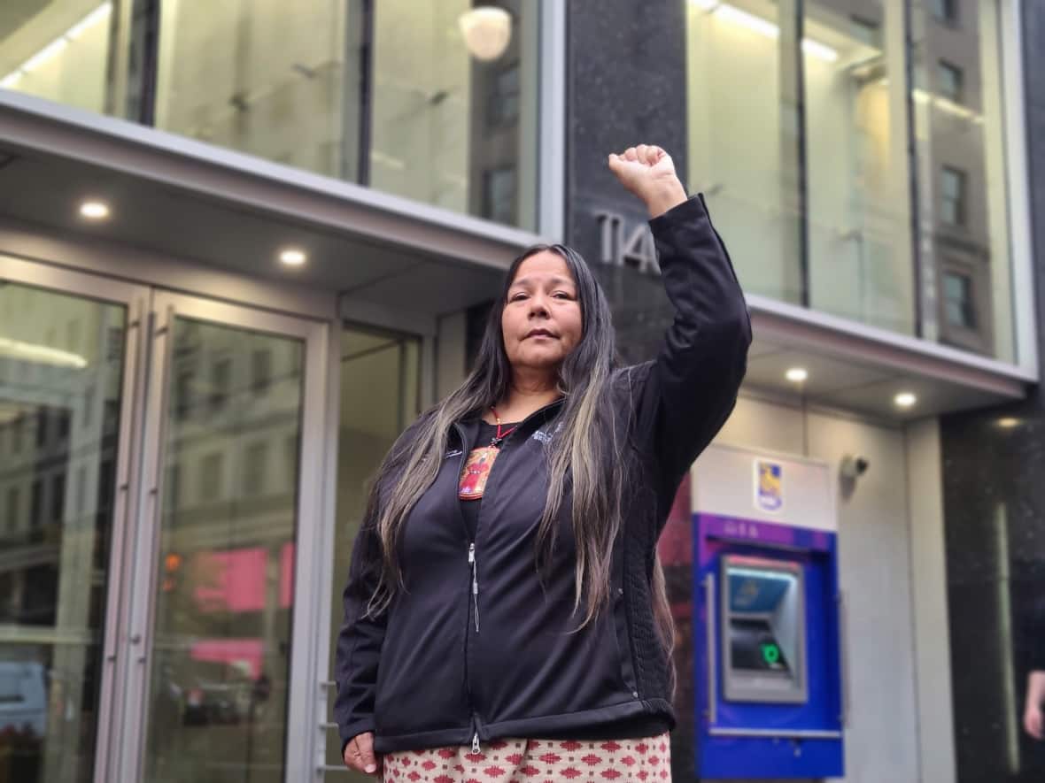 Kukpi7 (Chief) Judy Wilson of the Skat’sin te Secwepemc-Neskonlith Indian Band stands defiantly in front of an RBC branch in downtown Montreal. Wilson is part of a movement to hold banks accountable for funding the fossil fuel sector. (Jaela Bernstien/CBC - image credit)