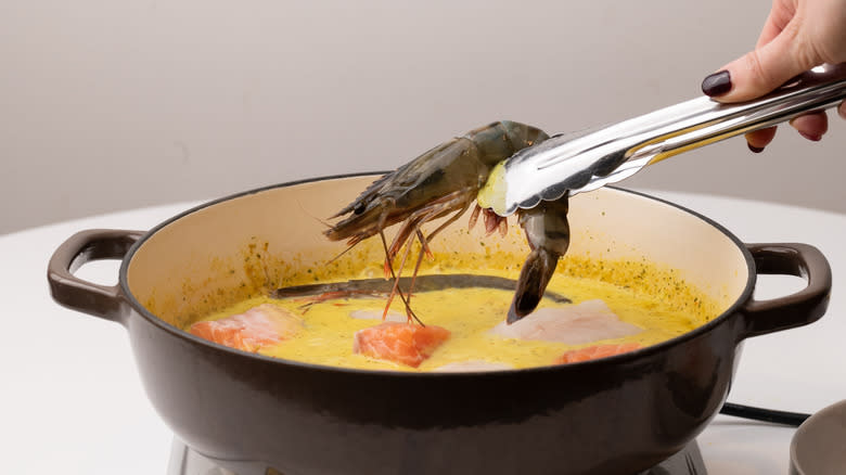 adding prawn to a pan