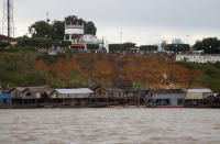 Illegal miners gather on the shore below the town of Borba after dozens of dredging barges were set on fire by officers of the Brazilian Institute of the Environment and Renewable Natural Resources, IBAMA, during an operation to try to contain illegal gold mining on the Madeira river, a tributary of the Amazon river in Borba, Amazonas state, Brazil, Sunday, Nov. 28, 2021. Hundreds of barges belonging to illegal miners had converged on the river during a gold rush in the Brazilian Amazon prompting IBAMA authorities to start burning them. (AP Photo/Edmar Barros)