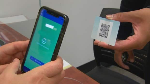 A student gets his proof of vaccination QR code scanned by a campus official at the University of Winnipeg. Just as COVID-19 vaccination policies vary between Canadian post-secondary institutions, what's greeting students on the ground as they head in for their lectures and labs also differs by school. (CBC - image credit)