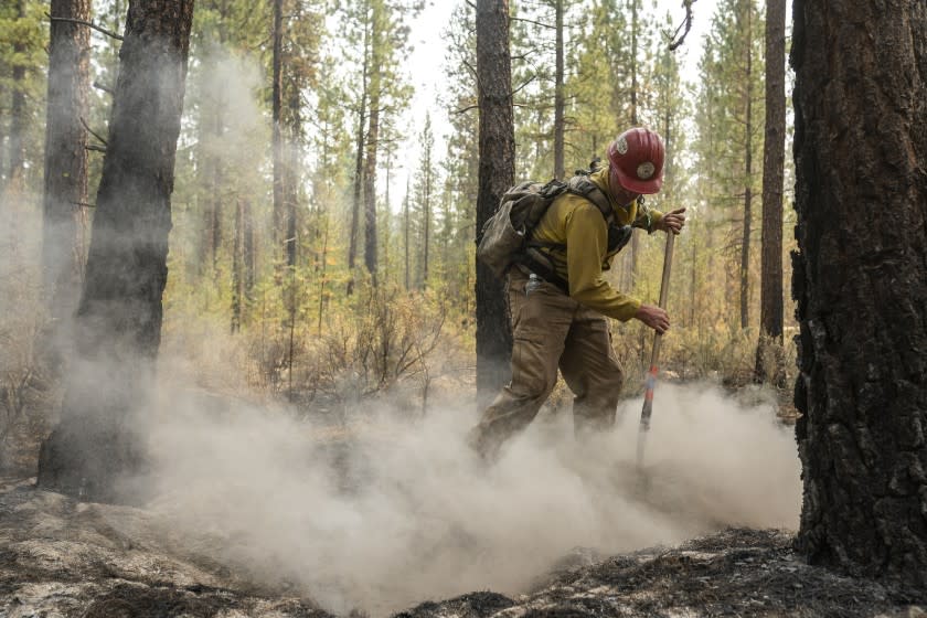 Firefighter Garrett Suza, with the Chiloquin Forest Service, mops up a hot spot on the North East side of the Bootleg Fire, Wednesday, July 14, 2021, near Sprague River, Ore. (AP Photo/Nathan Howard)