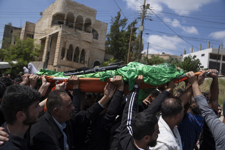 Mourners carry the body of Hamas local commander Mohammad Daraghmeh, 26, wrapped with a Hamas flag, during his funeral in the West Bank city of Tubas, Friday, April 12, 2024. Two Palestinians were killed early Friday in confrontations with Israeli forces in the Israeli-occupied West Bank, Palestinian medics and the Israeli military said. The Islamic militant group Hamas said one of those killed was a local commander. (AP Photo/Nasser Nasser)