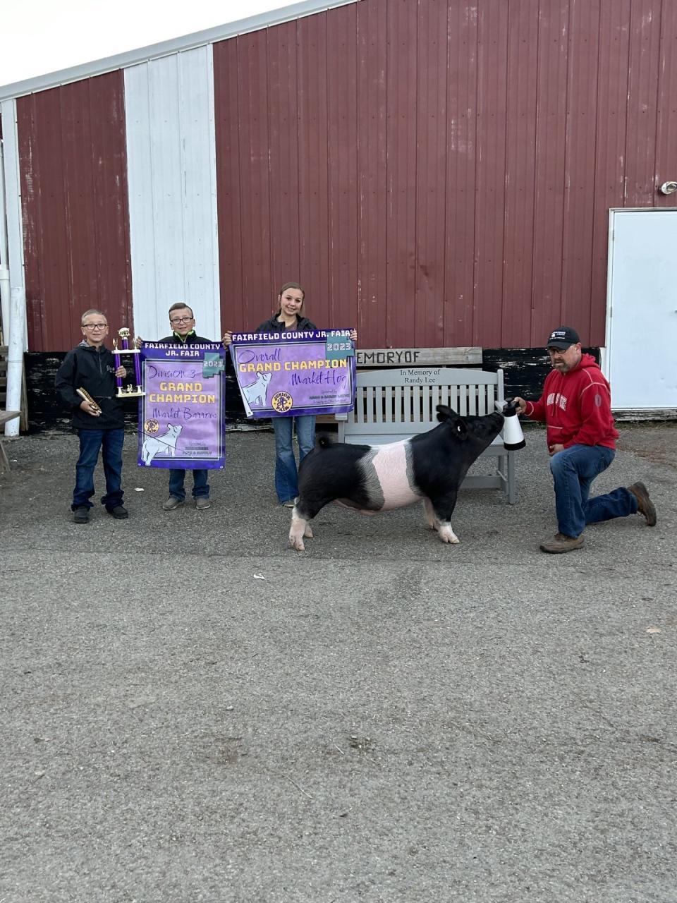 The Lee family stand with Grand Champion Hog Scoob beside a memorial bench dedicated to Randy Lee.