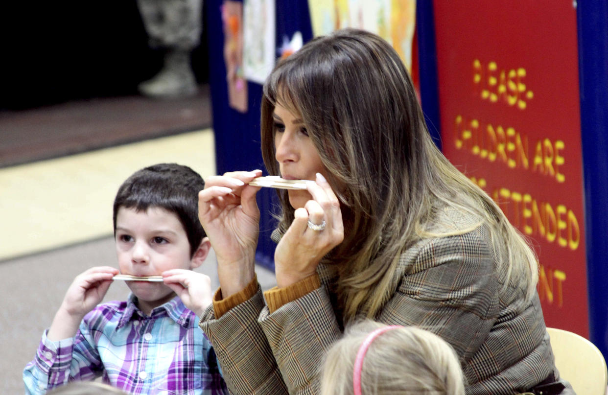 First lady Melania Trump plays a homemade harmonica with children at the Joint Base Elmendorf-Richardson, Alaska, on Nov. 10, 2017. (AP Photo/Mark Thiessen)