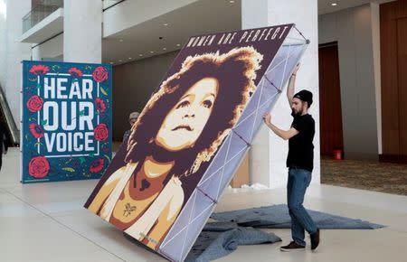 Zach Thompson helps to assemble a display of social justice images before the start of the three-day Women's Convention at Cobo Center in Detroit, Michigan, U.S., October 26, 2017. REUTERS/Rebecca Cook