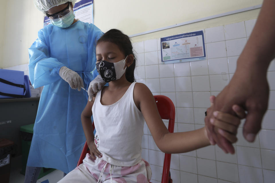 A young girl holds her mother's hand as she receives a shot of the Sinovac's COVID-19 vaccine at a Samrong Krom health center outside Phnom Penh, Cambodia, Friday, Sept. 17, 2021. Prime Minister Hun Sen announced the start of a nationwide campaign to give COVID-19 vaccinations to children between the ages of 6 and 11 so they can return to school safely after a long absence due to measures taken against the spread of the coronavirus. (AP Photo/Heng Sinith)