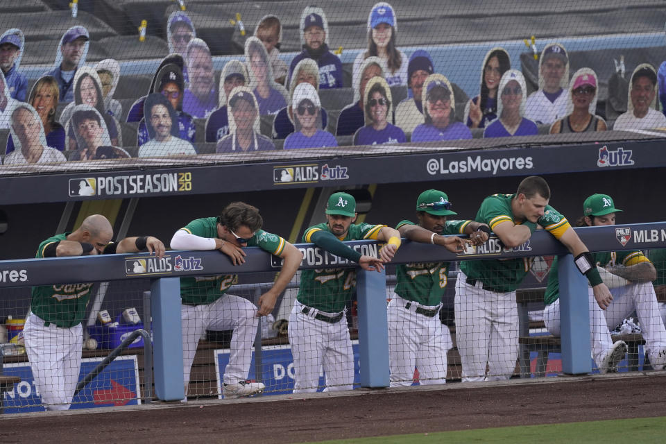 Oakland Athletics players stand in the dugout during the ninth inning of Game 2 of a baseball American League Division Series against the Houston Astros in Los Angeles, Tuesday, Oct. 6, 2020. (AP Photo/Ashley Landis)